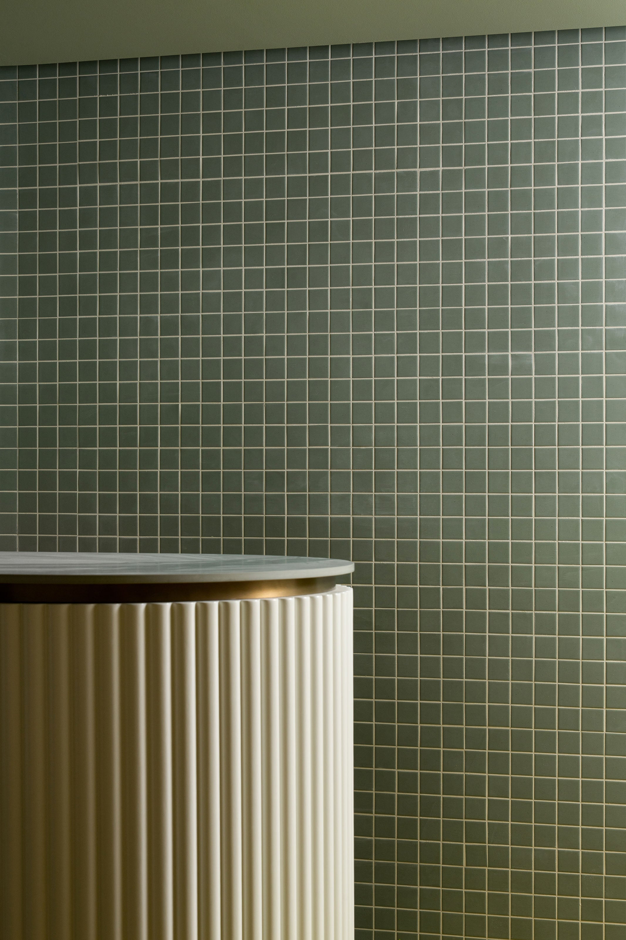 Green tiled wall of spa reception with a desk in the foreground