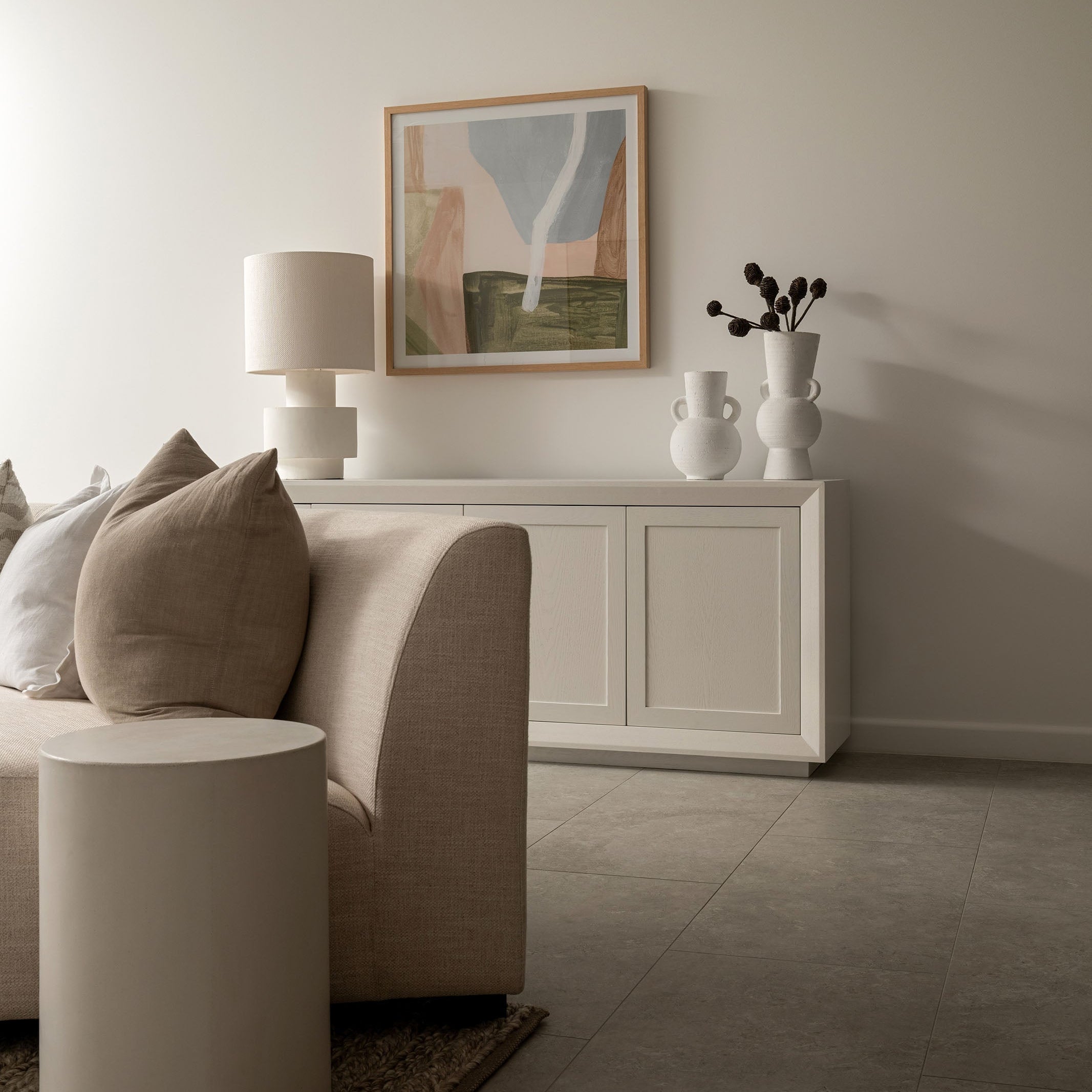 Modern living room with a beige sofa, side table, and abstract art on the wall.